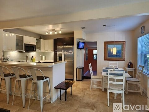 A kitchen with white chairs and a bar area.