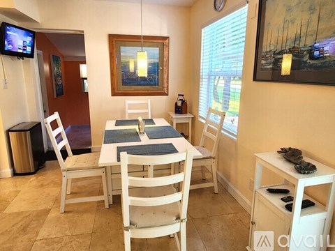 A dining room with a white table and chairs.