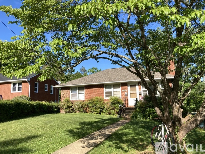 A tree in front of a red brick house.