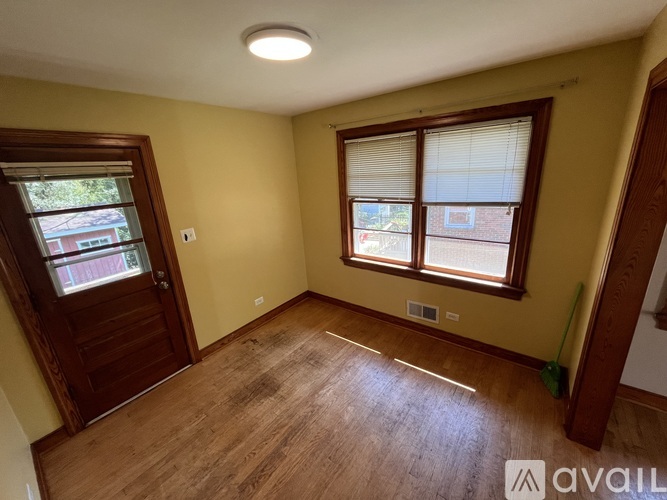 A room with a wooden floor and a window with blinds.