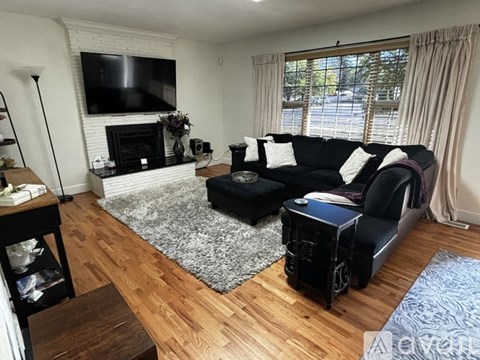 A living room with a black couch and a fireplace.
