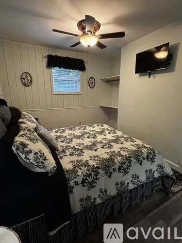 A bedroom with a bed, a ceiling fan, and a wall clock.