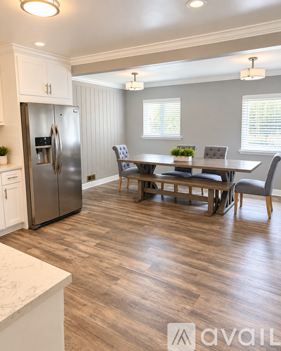 A kitchen with a refrigerator, table and chairs.