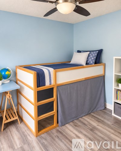 A bedroom with a bed, a ceiling fan, and a small table with a globe on it.