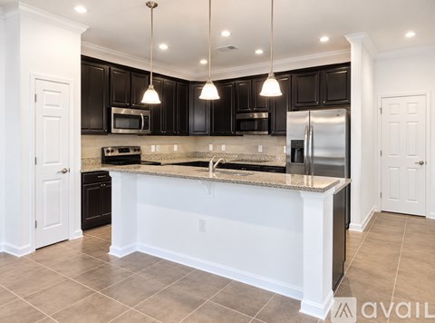 A kitchen with black cabinets and a white island.