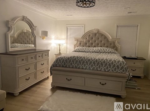 A bedroom with a bed, dresser, and mirror.