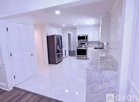 A kitchen with white cabinets and a marble floor.
