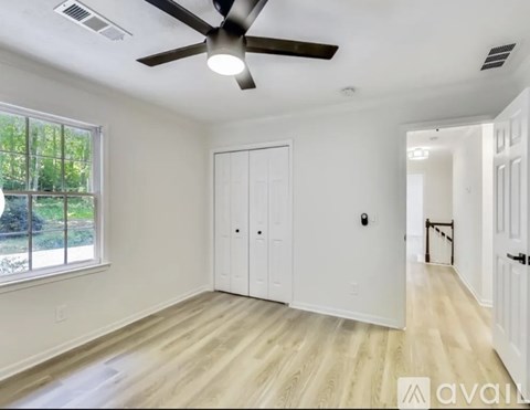 A room with a ceiling fan and a window with a view of trees.