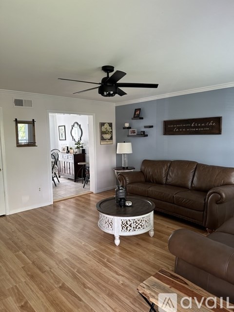 A living room with a brown leather couch and a white coffee table.