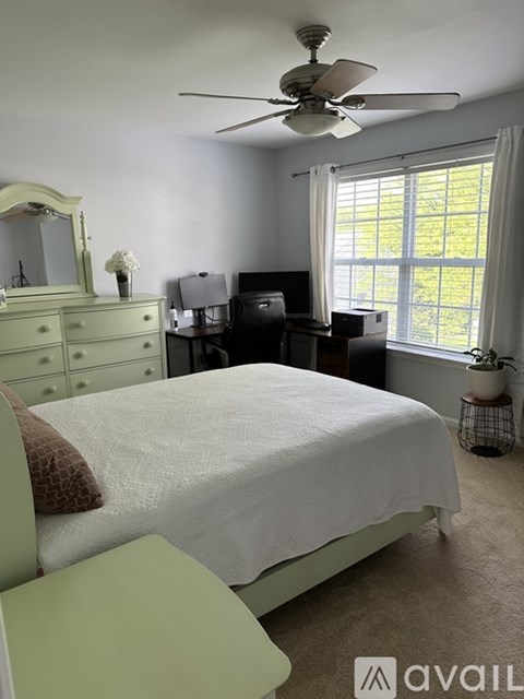 A bedroom with a bed, dresser, and window.