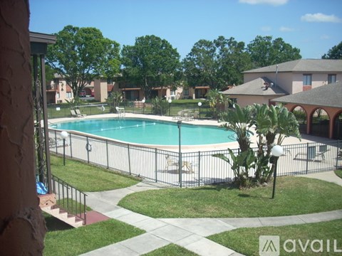 A pool surrounded by a fence and a green lawn.