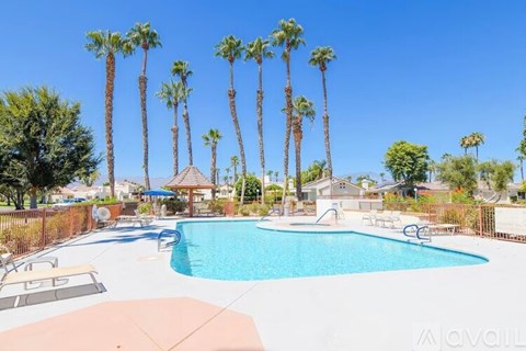 A pool surrounded by palm trees and a gazebo.
