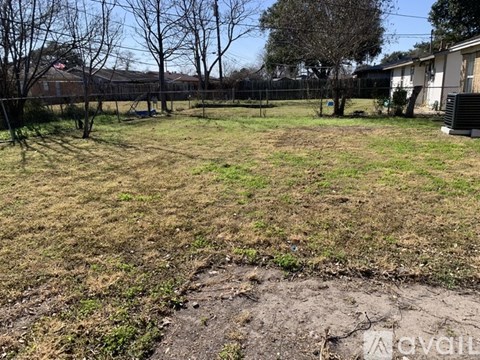 A grassy field with a dirt path in the middle and trees in the background.