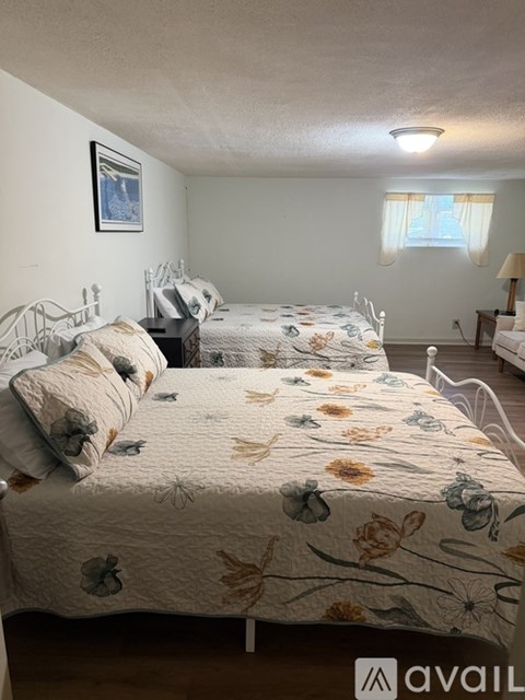 A bedroom with two beds and a nightstand.