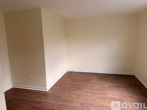A room with wooden flooring and white walls is available.