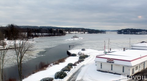 A white building with a red roof sits next to a snow-covered road.