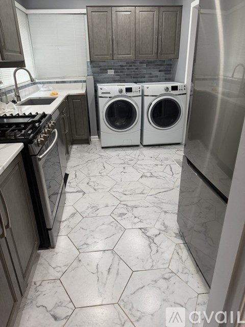 A kitchen with a marble floor and a stainless steel refrigerator.