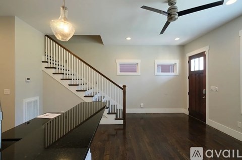 A spacious room with a staircase and a ceiling fan.
