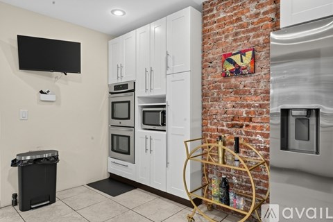 A kitchen with white cabinets and a brick wall.