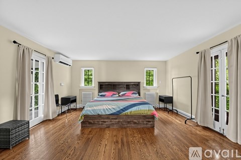 A bedroom with a large bed and wooden floors.