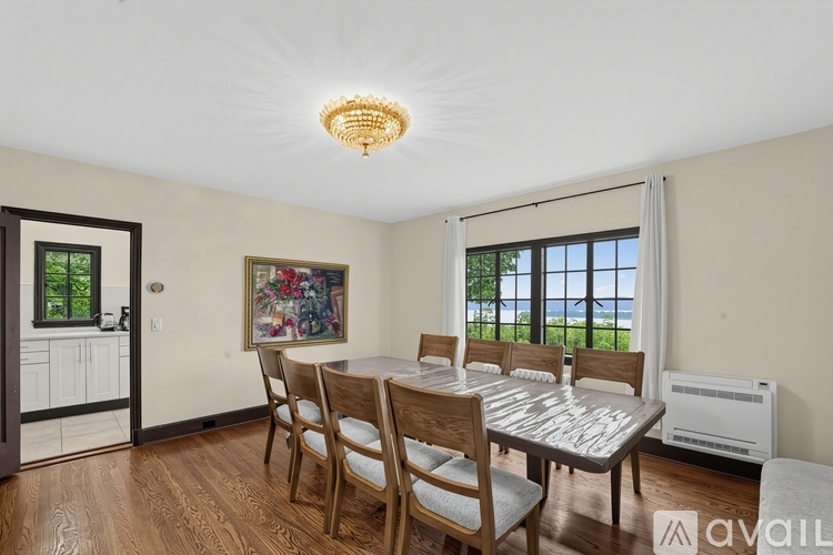 A dining room with a table and chairs and a painting on the wall.