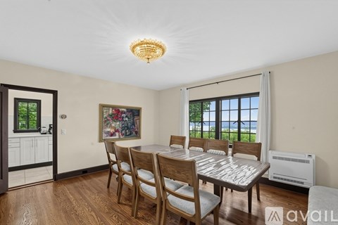 A dining room with a table and chairs and a painting on the wall.