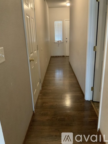 A long hallway with wood floors and white walls.