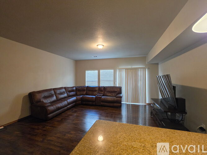 A living room with a brown leather couch and a wooden floor.