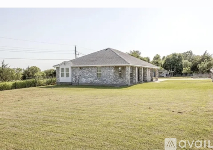 A house with a stone exterior is surrounded by a grassy yard.