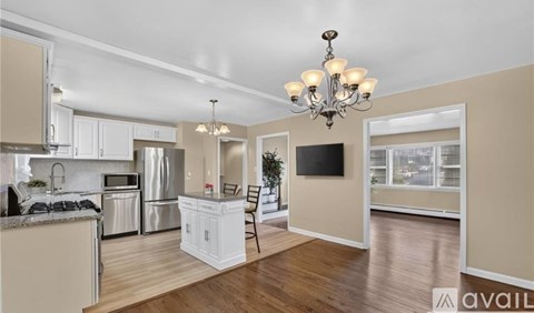 A well-lit kitchen with a dining area and a television in the living room.