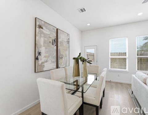 A modern dining room with a glass table and chairs.