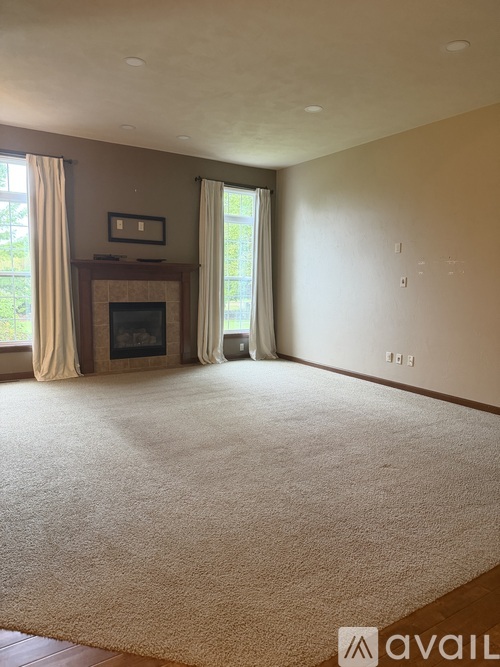A living room with a fireplace and a carpet on the floor.