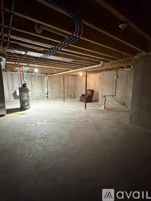 A spacious basement with a concrete floor and walls, equipped with a furnace and electrical conduits.