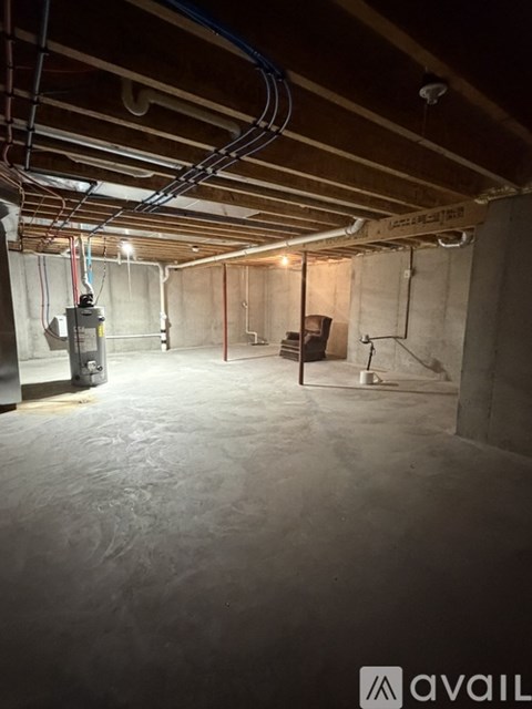 A spacious basement with a concrete floor and walls, equipped with a furnace and electrical conduits.