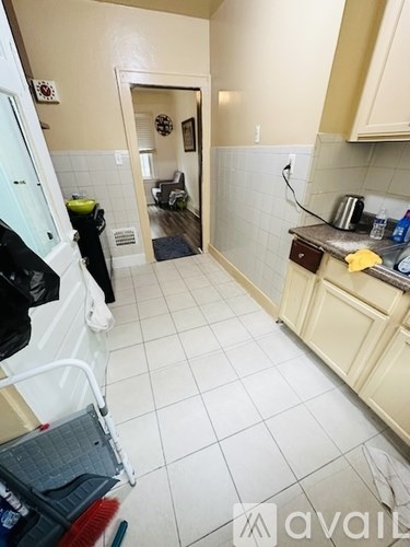 A kitchen with a white fridge and a white tile floor.