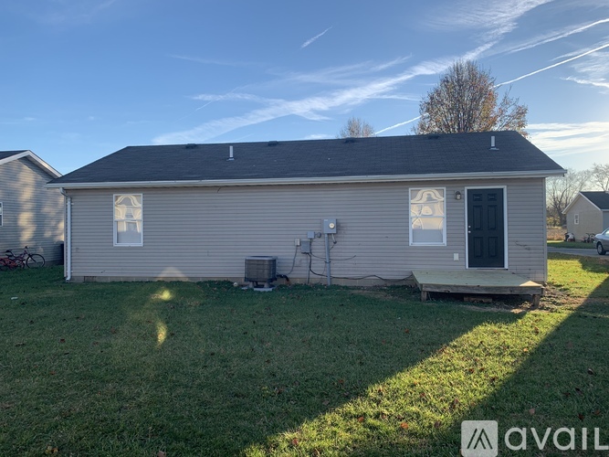 A house with a grey roof and a black door is available for rent.