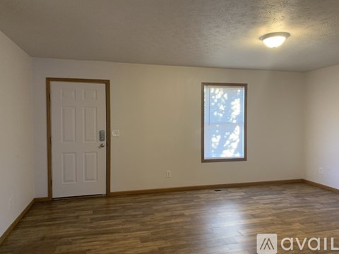 A room with a door and a window with wooden flooring.