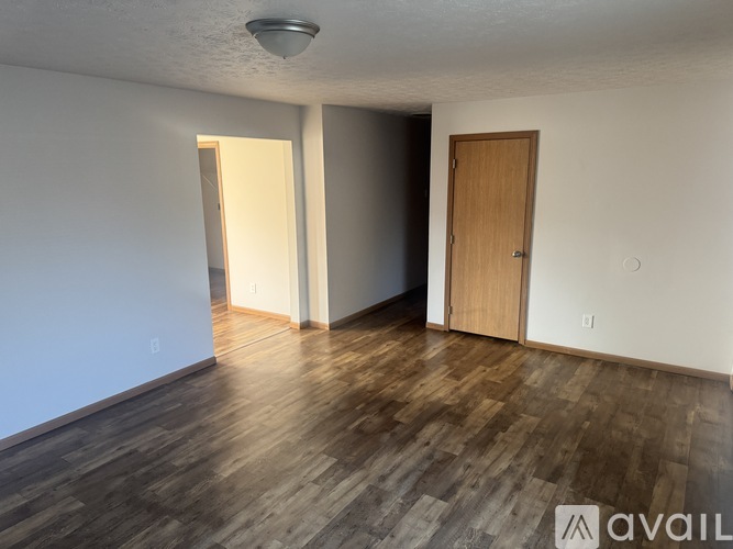 A room with wooden floors and a door on the right.