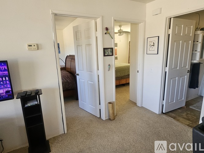 A living room with a television on the left and a doorway leading to another room.