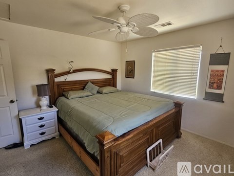 A bedroom with a bed, nightstand, and window with blinds.