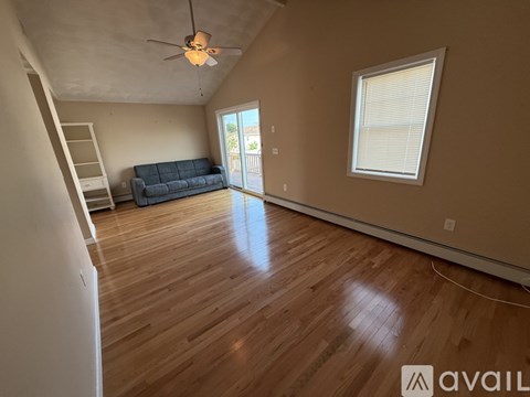 A living room with a blue couch and a ceiling fan.
