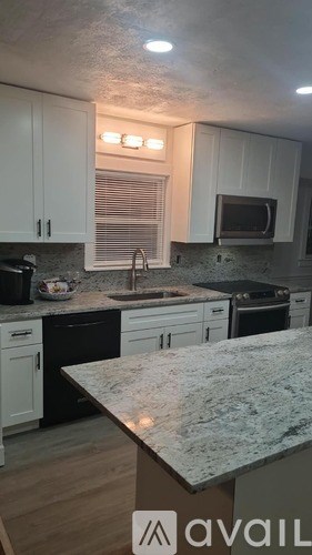 A kitchen with granite countertops and white cabinets.