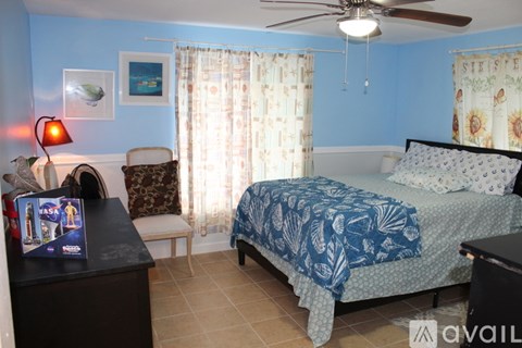 A bedroom with a bed, a chair, a dresser, and a ceiling fan.