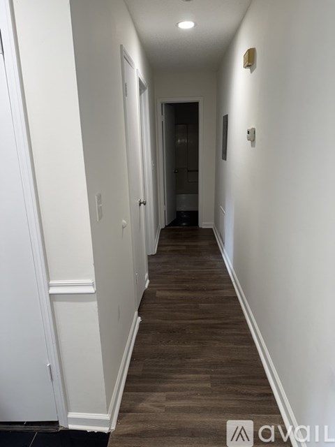 A long hallway with wood floors and white walls.