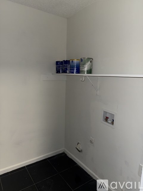 A room with a white wall and a shelf with two cans on it.