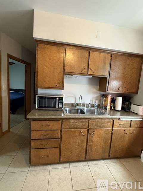 A kitchen with wooden cabinets and a microwave on the counter.