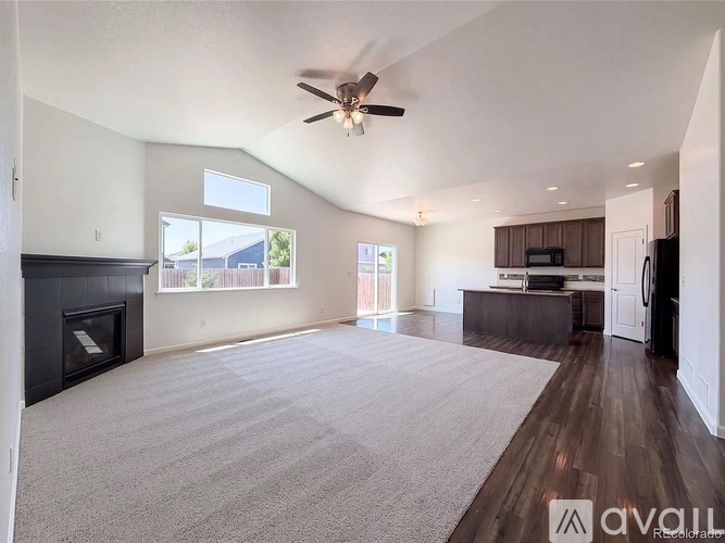 A spacious living room with a fireplace and a ceiling fan.