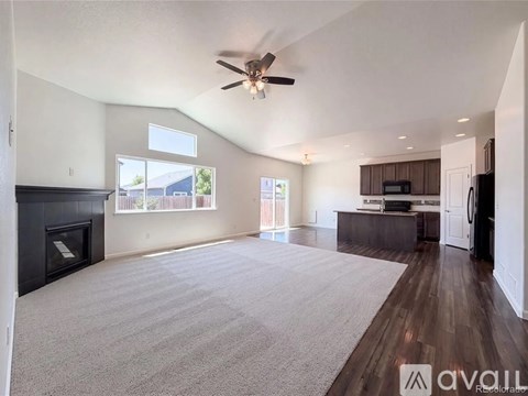 A spacious living room with a fireplace and a ceiling fan.