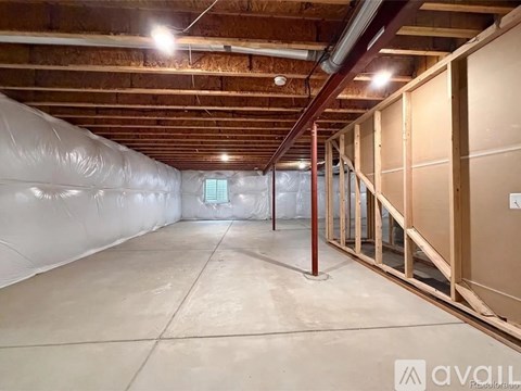 A spacious attic room with wooden beams and a concrete floor.