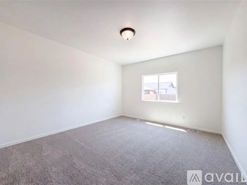 A room with a carpeted floor and a window showing a building outside.
